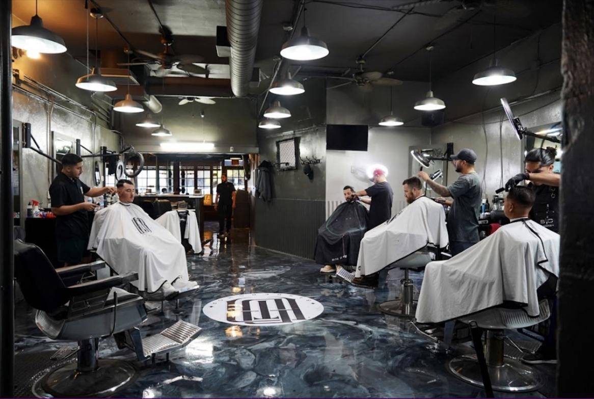 Inside DTR Cuts: barbers at work in a row of black chairs, with the DTR logo set into the marbled floor